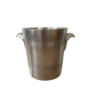 May include: A silver ice bucket with two handles. The bucket is cylindrical in shape and made of metal.