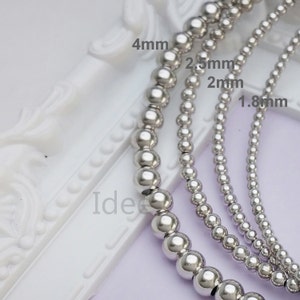 May include: Four strands of silver bead necklaces with different sized beads. The beads measure 1.8 mm, 2 mm, 2.5 mm, and 4 mm in diameter.
