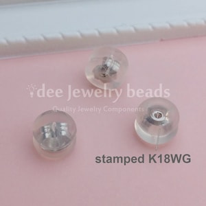 Op de afbeelding: Drie doorzichtige oorbelruggen met metalen componenten. De tekst "stamped K18WG" is zichtbaar. Het logo van "dee jewelry beads" is ook zichtbaar, samen met de tekst "Quality Jewelry Components".