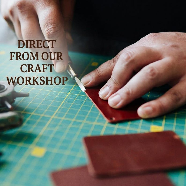 May include: A metal craft tool cutting a piece of dark red leather on a green cutting mat with grid lines. The text DIRECT FROM OUR CRAFT WORKSHOP is printed in brown letters on the left side of the image, positioned above the leather piece.