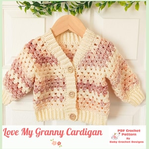 May include: A crochet cardigan featuring a granny square stitch pattern in variegated shades of cream, soft pink, and dusty rose. The garment has long sleeves, a ribbed hem and cuffs, and three wooden buttons down the front. Text reads: Love My Granny Cardigan.