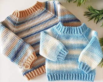 May include: Two handmade crochet sweaters. One is a larger size with tan, blue, and white stripes. The other is a smaller size with blue and white stripes. The sweaters have ribbed cuffs and necklines. The website www.babycrochetdesigns.com is visible.