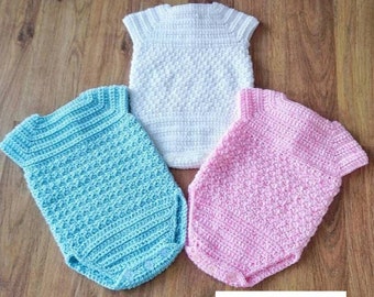 May include: Three crocheted baby onesies in white, light blue, and pink. The onesies have short sleeves and are made with a textured stitch. The text "Crochet PDF Pattern by BabyCrochetDesigns" is visible at the bottom of the image.