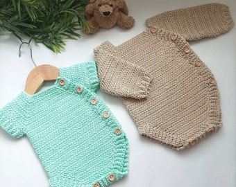 Op de afbeelding: Twee gehaakte baby-rompers, één in lichtgroen en één in beige. Beide rompers hebben houten knopen aan de voorkant.