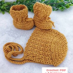 May include: A crocheted baby bonnet and booties set in a mustard yellow color. The bonnet has a long tie and the booties have a lace-up detail. Crochet PDF Pattern by BabyCrochetDesigns.