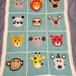 Peut inclure: Une couverture b&eacute;b&eacute; en crochet avec un fond bleu clair et une bordure blanche. La couverture pr&eacute;sente 12 carr&eacute;s avec diff&eacute;rents visages d'animaux, dont un lion, une girafe, un singe, un panda et un z&egrave;bre.