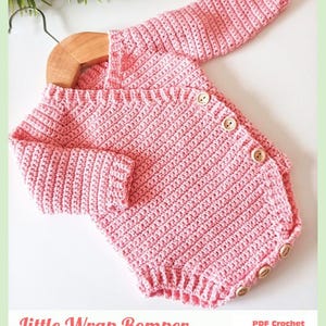 May include: A light pink long-sleeved crochet romper featuring a wrap-style front with four wooden buttons along the side and three wooden buttons at the bottom. The text reads Little Wrap Romper PDF Crochet Pattern By Baby Crochet Designs.