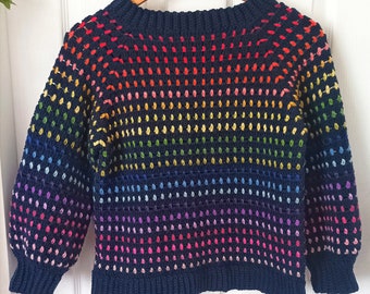 Peut inclure: Un pull en crochet bleu marine avec un motif arc-en-ciel de points colorés. Le pull a un col rond et des manches longues. Le texte "www.babycrochetdesigns.com" est imprimé en bas du pull.