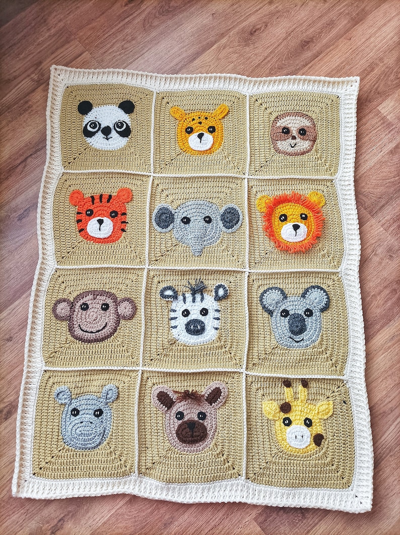 Peut inclure: Une couverture pour b&eacute;b&eacute; en crochet avec une bordure blanche et un centre beige. La couverture pr&eacute;sente une grille de 12 carr&eacute;s, chacun avec un visage d'animal diff&eacute;rent crochet&eacute; au centre. Les animaux comprennent un panda, un lion, un tigre, un &eacute;l&eacute;phant, un z&egrave;bre, un singe, un koala, une girafe, un paresseux, un hippopotame, un gu&eacute;pard et un ours brun.