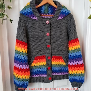 May include: A grey hooded cardigan with rainbow stripes on the sleeves and pockets. The cardigan has red buttons and is crocheted.