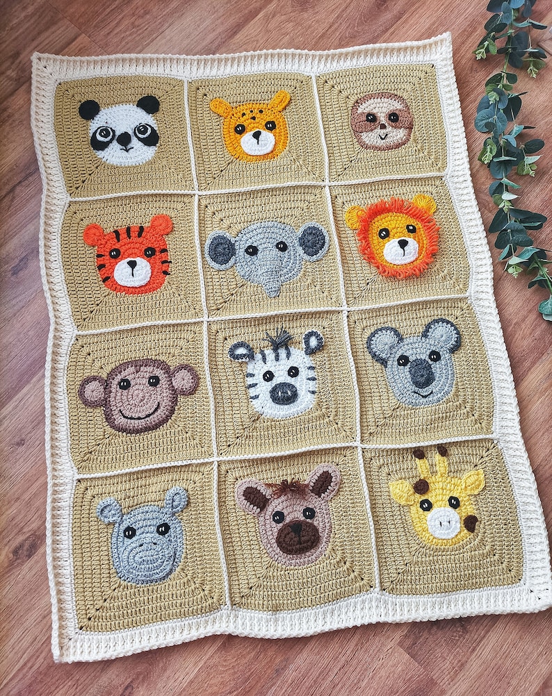 Peut inclure: Une couverture b&eacute;b&eacute; en crochet avec un fond beige et une bordure blanche. La couverture pr&eacute;sente 12 visages d'animaux diff&eacute;rents, dont un panda, un tigre, un &eacute;l&eacute;phant, un singe, un z&egrave;bre, un koala, une girafe et un hippopotame.