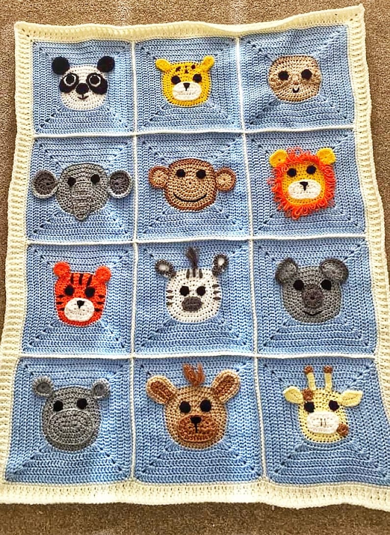 Peut inclure: Une couverture pour b&eacute;b&eacute; en crochet bleu et blanc avec diff&eacute;rents visages d'animaux, dont un panda, un singe, un lion, un z&egrave;bre, un tigre, un hippopotame, une girafe et un ours.