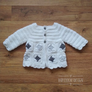 Puede incluir: Un cárdigan de bebé blanco tejido a crochet con detalles en forma de estrella gris y cierre de botón. BABY CROCHET DESIGN está escrito en la parte inferior de la imagen.
