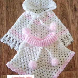 Può includere: Poncho per neonato in crochet bianco e rosa con cappuccio e pon pon. Modello PDF a uncinetto di BabyCrochetDesigns.