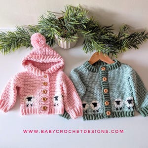 May include: Two crochet baby sweaters. One is pink with a hood and a pom-pom, the other is green. Both have wooden buttons and a sheep design on the bottom. The website www.babycrochetdesigns.com is visible.