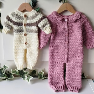 Op de afbeelding: Twee handgemaakte babyrompers. Eén is ivoor met bruine en grijze strepen, de andere is effen roze. Beide hebben lange mouwen, knoopsluitingen en worden op houten kleerhangers getoond.
