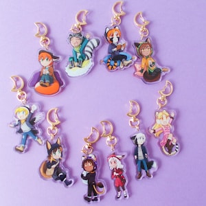 May include: A set of 10 colourful character keychains with gold crescent moon charms. Each keychain features a different character with unique clothing and accessories.