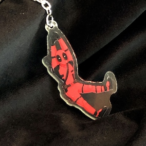 May include: A red and black character keychain with a silver chain. The character is in a dynamic pose with one leg raised and arms outstretched.