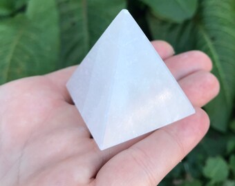 Puede incluir: Una pirámide de cristal de selenita blanca, un tipo de mineral conocido por sus propiedades calmantes y purificadoras.