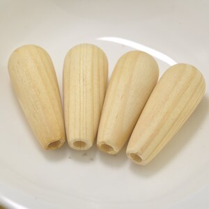 Puede incluir: Cuatro terminales de madera natural con forma de lágrima. Los terminales son lisos y tienen una veta de madera clara.