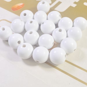 May include: A pile of white wooden beads with a hole in the center of each bead.