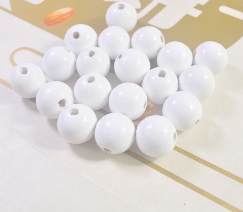 May include: A pile of white wooden beads with a hole in the center of each bead.