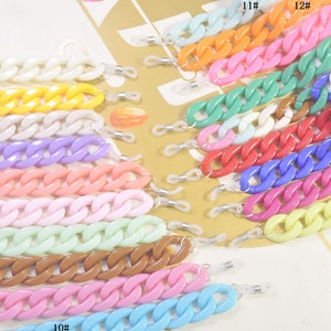 Pode incluir: Dezenove correntes de plástico coloridas com fechos de metal. As correntes são de várias cores, incluindo branco, amarelo, roxo, rosa, azul claro, marrom e verde. As correntes são numeradas de 1 a 19.