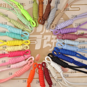 May include: A selection of brightly coloured corded zipper pulls, featuring shades like pink, orange, red, green, and blue. Each pull is numbered from 1 to 29. The cords are tightly wound and looped at the end.
