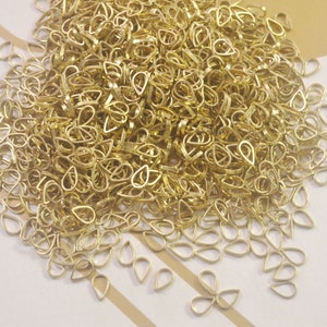 Puede incluir: Un montón grande de baúles de colgantes de metal de color dorado en forma de lágrima. Los baúles son pequeños y delicados, y son perfectos para agregar un toque de elegancia a cualquier proyecto de joyería.