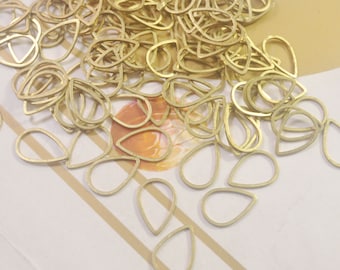 May include: A large pile of gold-colored metal teardrop-shaped charms. The charms are all the same size and shape, and they are arranged in a random pattern.