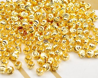 May include: A large pile of gold-colored metal beads. The beads are round and have a slightly textured surface.