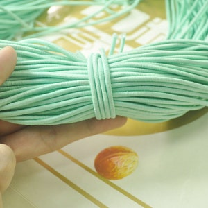May include: A close-up of a spool of light green elastic cord. The cord is soft and flexible, and it is ideal for making jewellery, crafts, and other projects.
