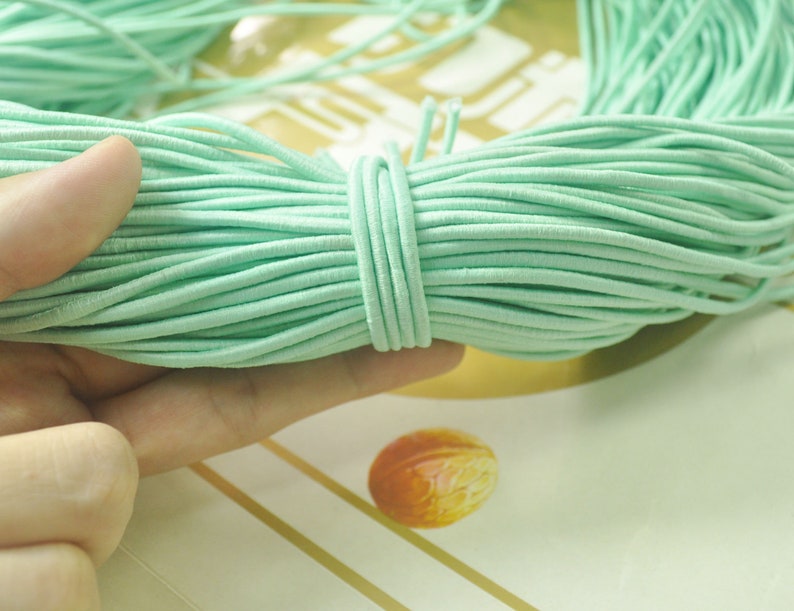 May include: A close-up of a spool of light green elastic cord. The cord is soft and flexible, and it is ideal for making jewellery, crafts, and other projects.