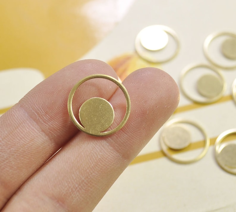 Puede incluir: Encanto de metal dorado en forma de c&iacute;rculo con un c&iacute;rculo m&aacute;s peque&ntilde;o en el interior. El encanto tiene un dise&ntilde;o minimalista y es perfecto para la elaboraci&oacute;n de joyas.
