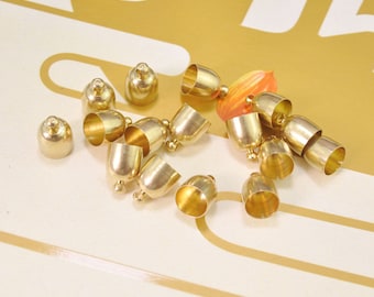 Puede incluir: Una colección de tapas de extremo de metal dorado para la elaboración de joyas. Las tapas son redondas y tienen un acabado liso y pulido.