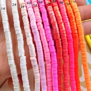 Pu&ograve; includere: Assortimento di 11 fili di perline di plastica iridescente colorate. Le perline sono piccole e rotonde, e sono disposte in fila dal bianco all'arancione. Le perline sono tutte della stessa dimensione e forma, e sono infilate su uno spago trasparente.