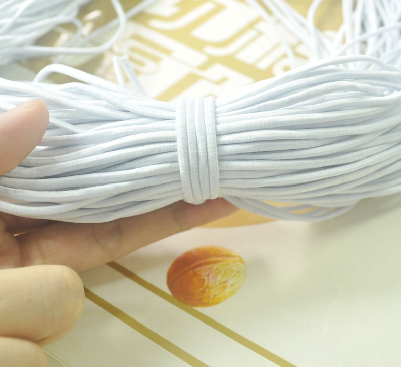 May include: A close-up of a bundle of white elastic cord. The cord is soft and flexible, and it is ideal for crafting projects.