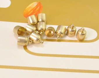 Puede incluir: Un grupo de 10 tapones de metal dorado para cordones o fabricación de joyas. Los tapones son redondos y tienen un pequeño agujero en el centro.