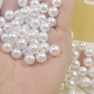 Pode incluir: Um monte de contas de pérola branca, perfeitas para fazer joias ou adicionar um toque de elegância a qualquer projeto.