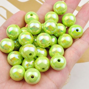 May include: A collection of 20 large, round, lime green iridescent plastic beads. The beads have a smooth, glossy finish and a small hole in the center.