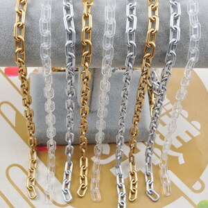 May include: A close-up of six chains, two gold, two silver, and two clear plastic. The chains are displayed on a white surface.