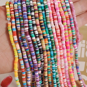 Può includere: Una collezione di 18 perline rotonde in argilla polimerica multicolori e multi-striate. Le perline sono infilate su un filo e sono disposte in fila. Le perline sono numerate da 50 a 68.