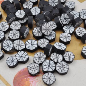 Puede incluir: Un conjunto de cuentas hexagonales negras con un diseño de telaraña blanca. Las cuentas son pequeñas y tienen un agujero para ensartar. Ideales para la creación de joyas u otros proyectos de artesanía.