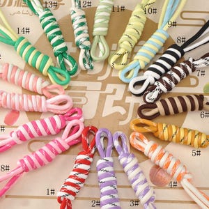 May include: A selection of colourful, braided cords with loops, in various combinations. The cords are numbered 1 to 18, with colours including red, white, pink, green, yellow, and black. The cords are likely for crafting or jewellery making.