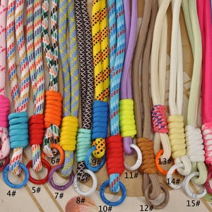 Puede incluir: Una colección de cordones coloridos con varios patrones y colores de cuerda, incluyendo amarillo, morado, rosa y azul. Cada cordón tiene un anillo del mismo color y una etiqueta numerada.