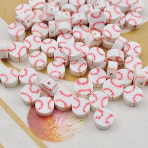 Könnte beinhalten: Eine große Gruppe weißer Plastikperlen mit rotem Baseball-Stichdesign. Die Perlen sind auf einer braunen Oberfläche verstreut.