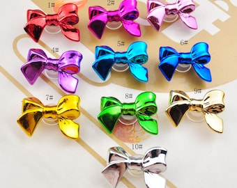May include: Ten metallic bow-shaped charms in various colors, including red, pink, blue, green, gold, and silver. Each charm is numbered 1 through 10.