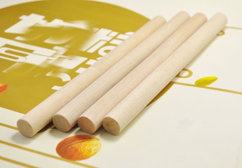 Puede incluir: Cuatro listones de madera natural, de aproximadamente 30 cm de largo, est&aacute;n dispuestos en una pila sobre una superficie dorada y blanca. Los listones son lisos y tienen un color marr&oacute;n claro.