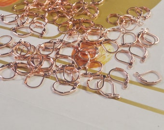 May include: A pile of rose gold earring hooks. The hooks are made of metal and have a spring-loaded clasp.
