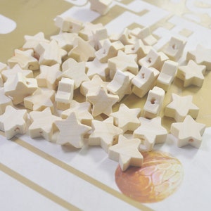 May include: A large pile of wooden star-shaped beads in a light cream colour. The beads have a hole in the centre for stringing.